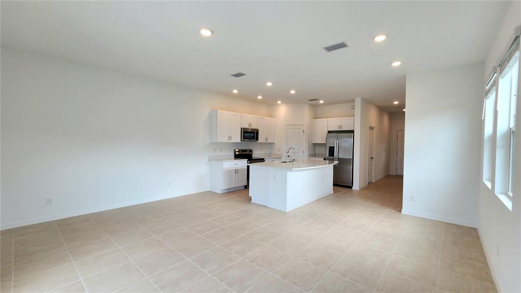 A modern kitchen with white cabinets, stainless steel appliances, and an island in an open room — 16656 BERGAMO PLACE, LAKEWOOD RANCH, FL