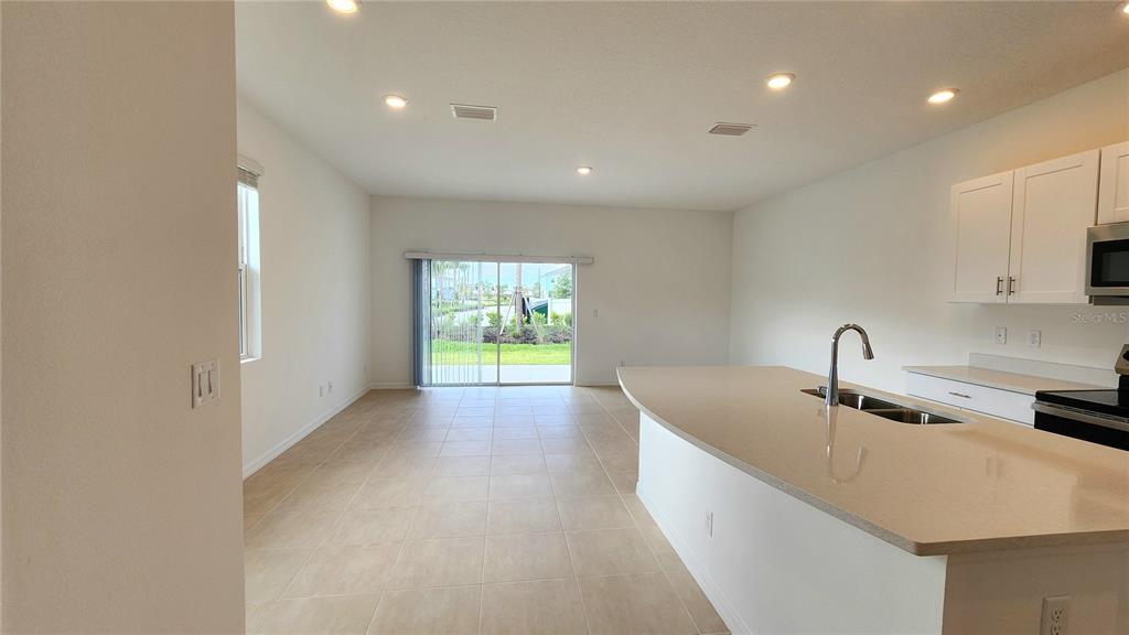 A kitchen with a large island and light-colored cabinets overlooks an open living area — 16656 BERGAMO PLACE, LAKEWOOD RANCH, FL