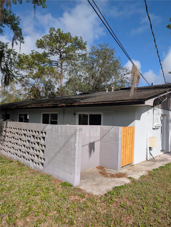 An exterior view of a single-story building with a concrete block wall and wooden gate — 805 NW 40TH AVENUE, GAINESVILLE, FL