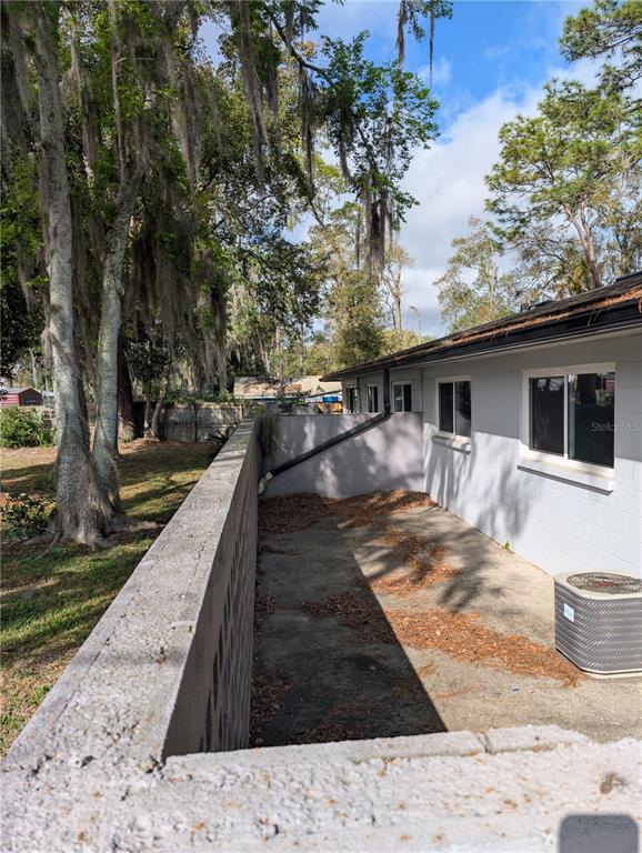 A concrete patio area sits between a cinder block wall and the side of a house — 805 NW 40TH AVENUE, GAINESVILLE, FL