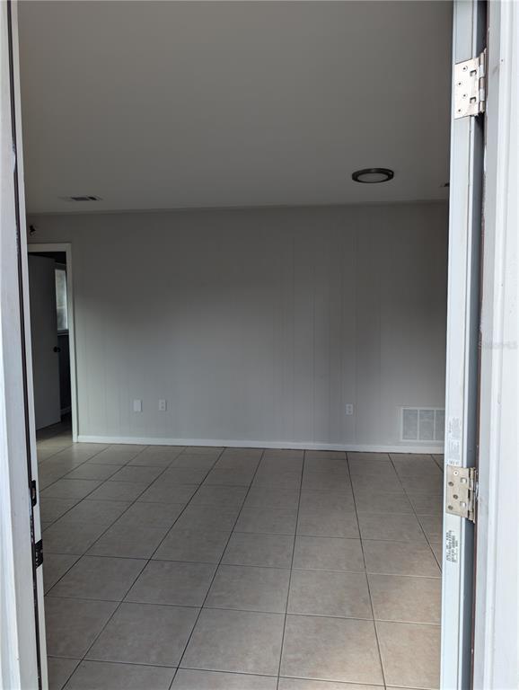 A view through a doorway into a room with light gray walls and tiled flooring — 805 NW 40TH AVENUE, GAINESVILLE, FL