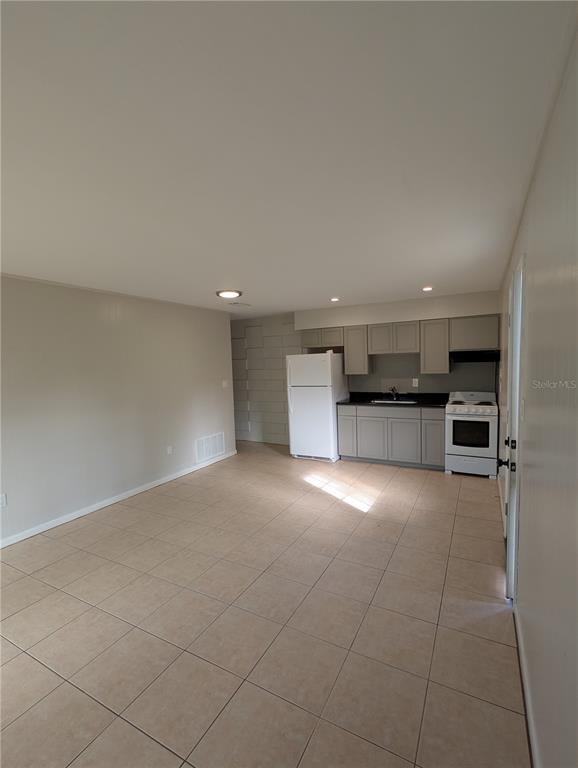 An open-concept kitchen and living area features light-colored tile flooring and gray cabinetry — 805 NW 40TH AVENUE, GAINESVILLE, FL