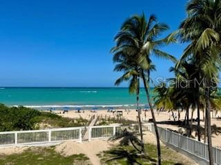An elevated view of a sandy beach with palm trees and a white wooden fence — 4837 AVE. ISLA VERDE UNIT 209, CAROLINA, PR