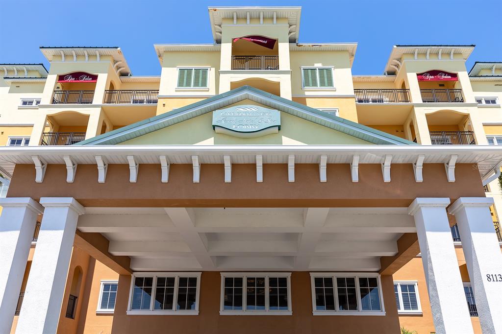 A low-angle exterior view of a multi-story hotel building with a prominent lobby entrance — 8100 POINCIANA BOULEVARD UNIT 2312, ORLANDO, FL