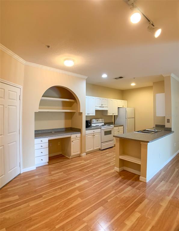 A kitchen with white cabinets, light wood floors, and a built-in desk area — 860 N ORANGE AVENUE UNIT 428, ORLANDO, FL