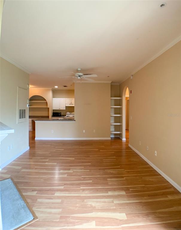A living room with light wood flooring leads to an open kitchen with white cabinets — 860 N ORANGE AVENUE UNIT 428, ORLANDO, FL