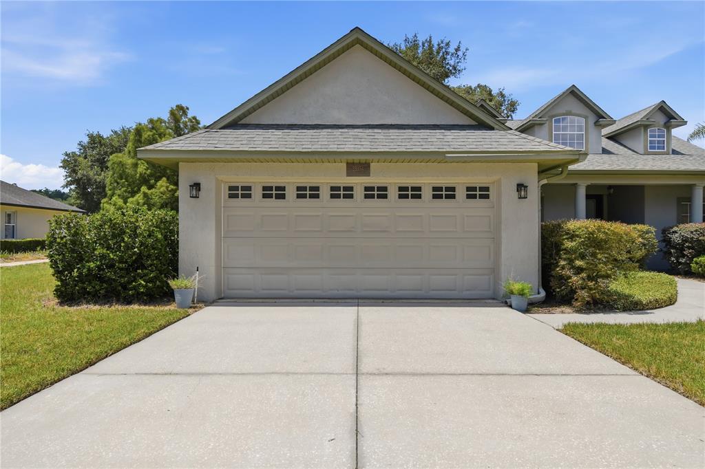 A beige two-car garage with a concrete driveway and a gabled roof — 23354 OAK PRAIRIE CIRCLE, SORRENTO, FL
