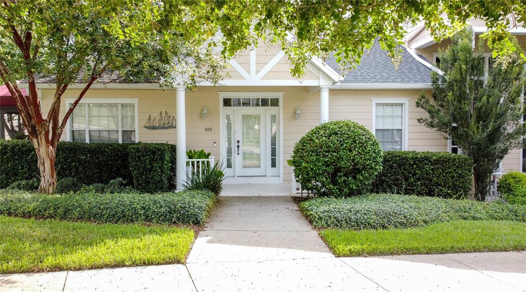 A single-story house with beige siding, a white front door, and manicured landscaping — 102 CARRICK BEND WAY, CLERMONT, FL