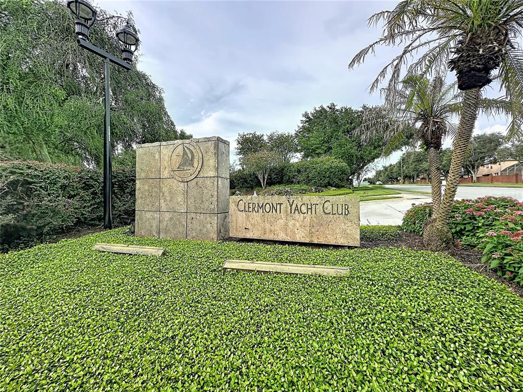 A stone monument sign for the Clermont Yacht Club stands in a landscaped garden area — 102 CARRICK BEND WAY, CLERMONT, FL