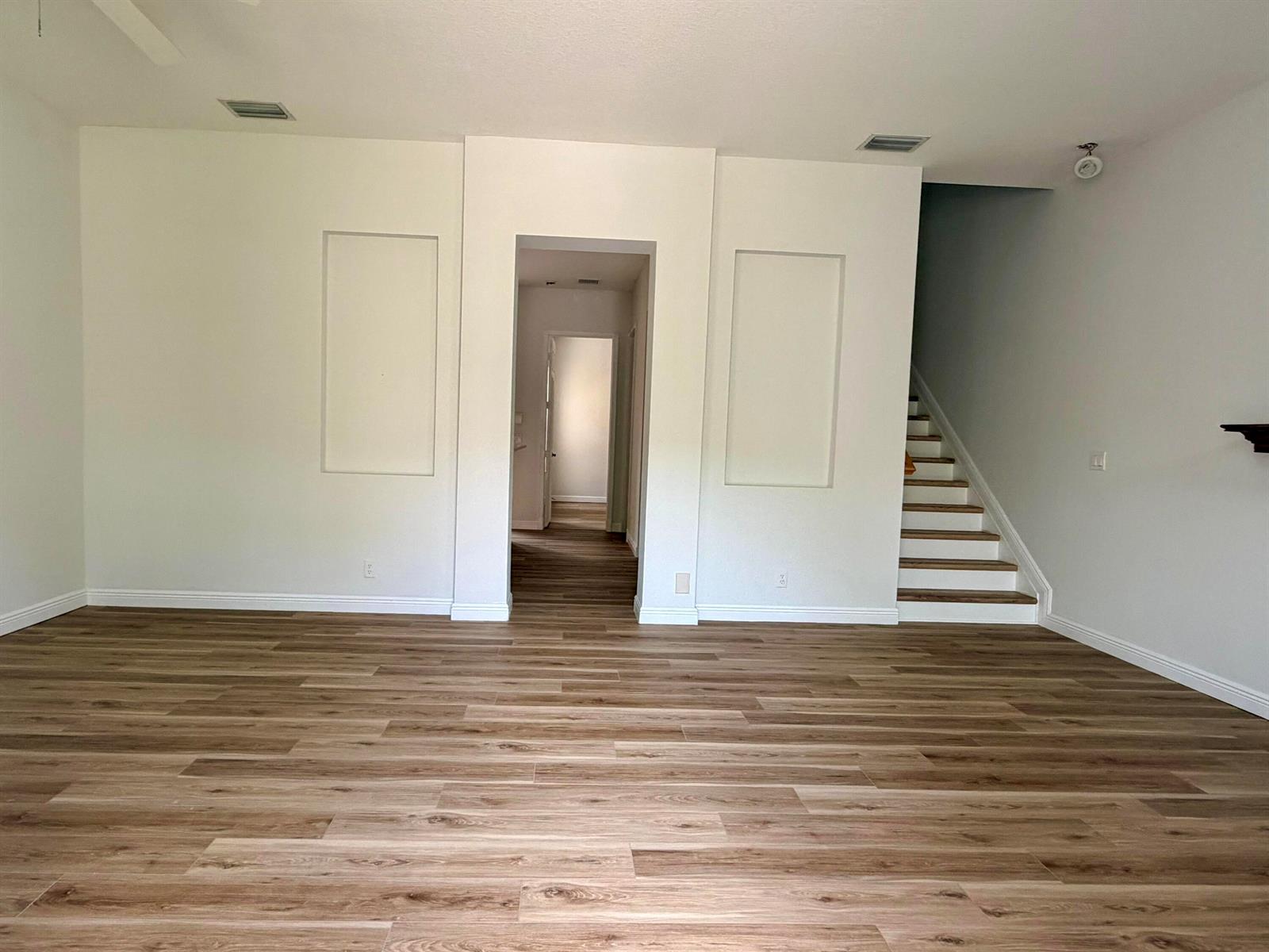 A living room with wood-look flooring, two wall niches, and a staircase — 814 NW 82nd Place, Boca Raton FL 33487, BOCA RATON, FL
