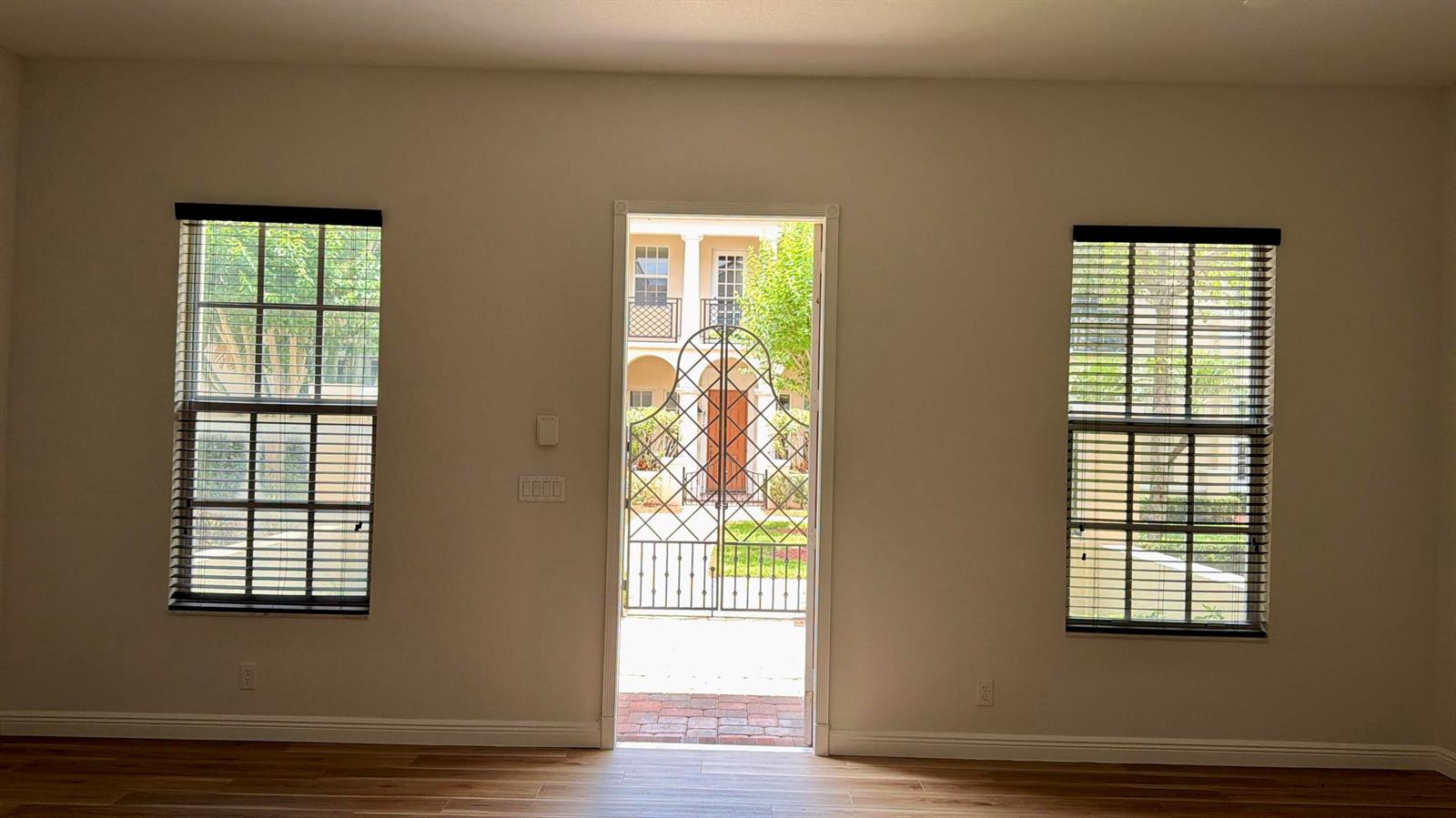 A room with light-colored walls, wood-look flooring, two windows with blinds, and an open doorway — 814 NW 82nd Place, Boca Raton FL 33487, BOCA RATON, FL