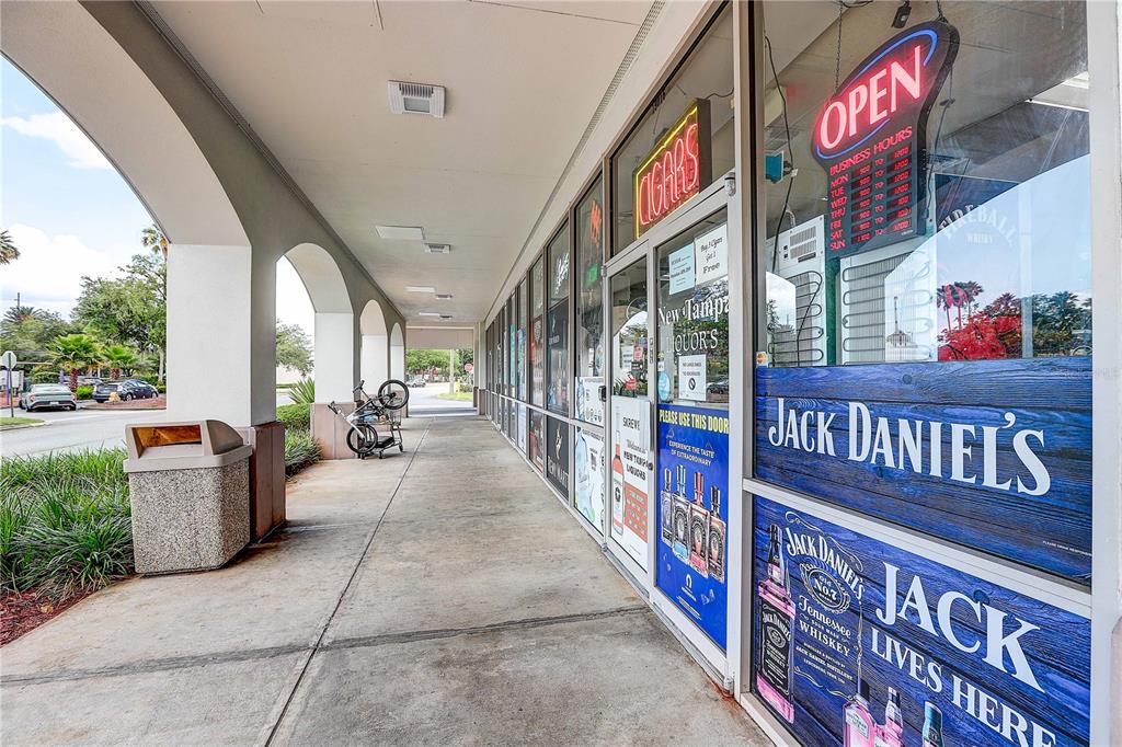 A concrete walkway runs along the exterior storefront of a liquor store with glass doors — BRUCE B DOWNS BOULEVARD, TAMPA, FL