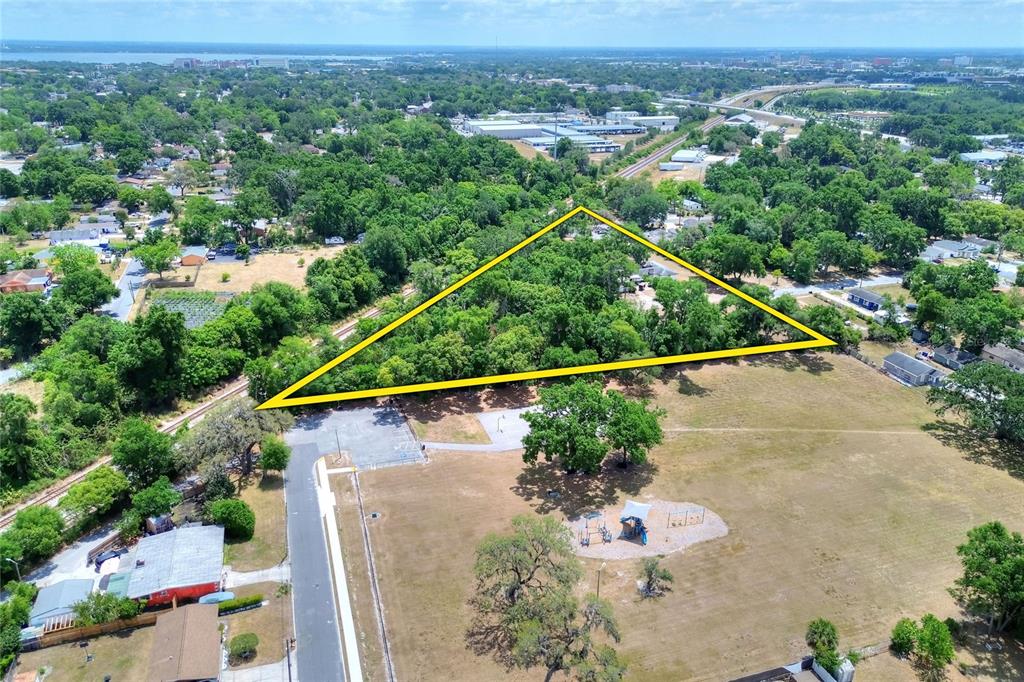 An aerial view shows a triangular plot of land highlighted in yellow near a park — 1205 NEVILLE AVENUE, LAKELAND, FL