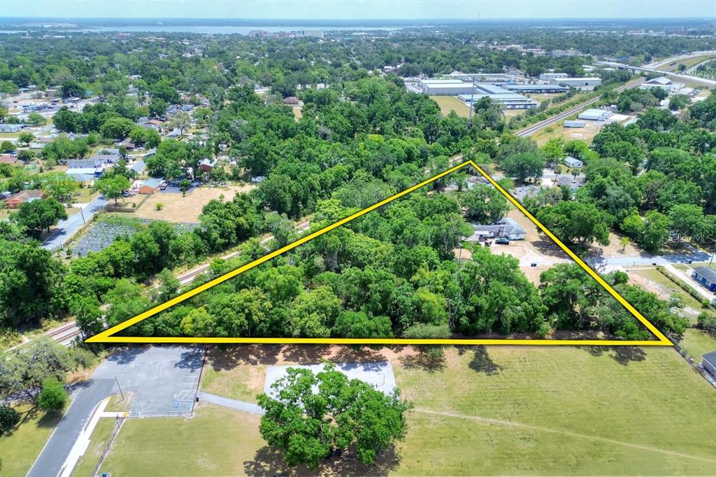 An aerial view shows a triangular plot of land densely covered with trees and vegetation — 1205 NEVILLE AVENUE, LAKELAND, FL