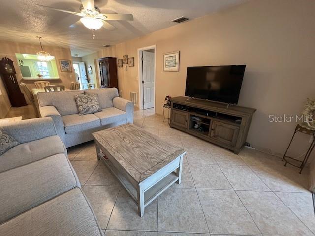 A living room features light-colored tile flooring, a gray sofa, and a wooden media console — 2666 WOODGATE LANE UNIT D-1, SARASOTA, FL