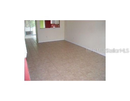 An interior view shows a room with beige tile flooring and a kitchen pass-through window — 4204 PLANTATION COVE DRIVE, ORLANDO, FL