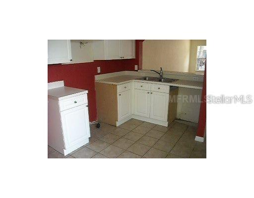 A kitchen features white cabinets, a double-basin sink, and red walls over tiled flooring — 4204 PLANTATION COVE DRIVE, ORLANDO, FL