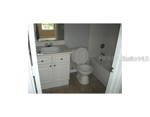 A bathroom features a white vanity with a sink, a toilet, and a bathtub — 4204 PLANTATION COVE DRIVE, ORLANDO, FL