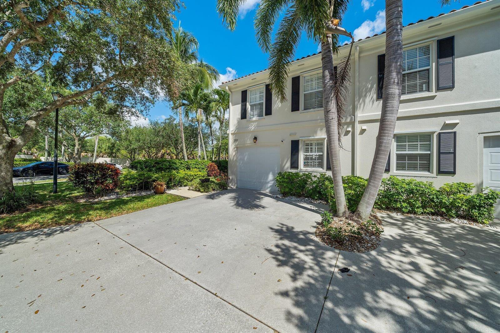 A two-story townhouse with a white garage, palm trees, and a concrete driveway — 2117 Tigris Drive, West Palm Beach FL 33411, WEST PALM BEACH, FL