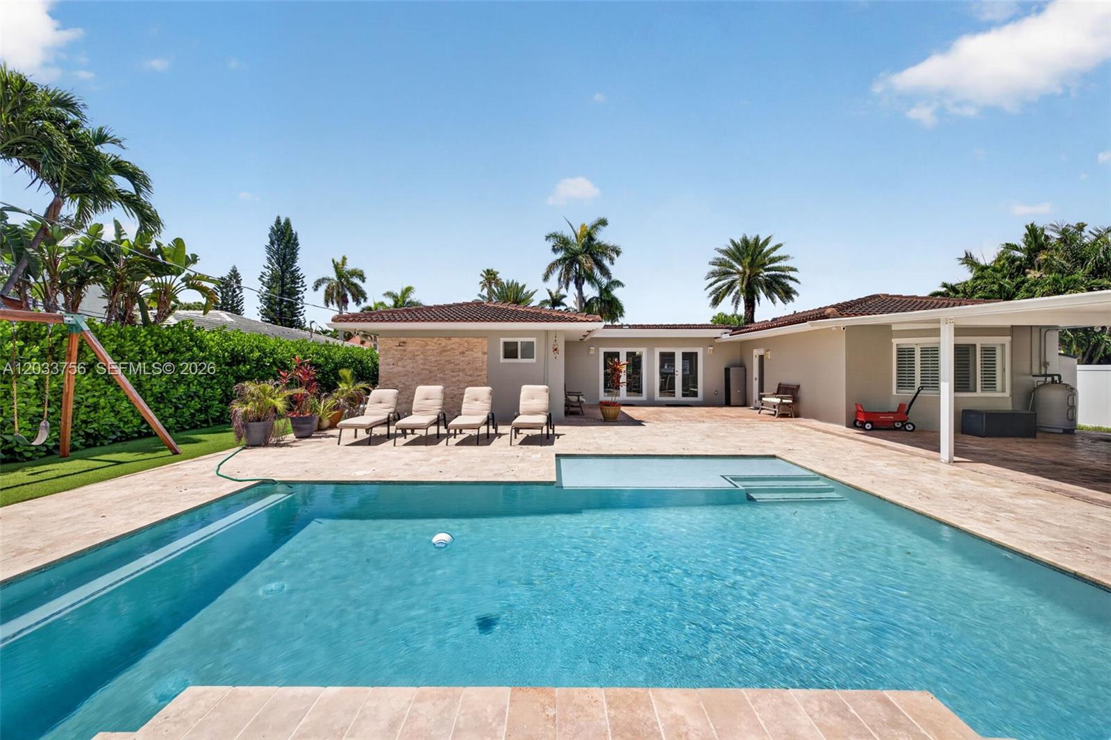 A backyard features a swimming pool, patio, lounge chairs, and a single-story house exterior — 313 SE 6th St, Dania Beach FL 33004, DANIA BEACH, FL