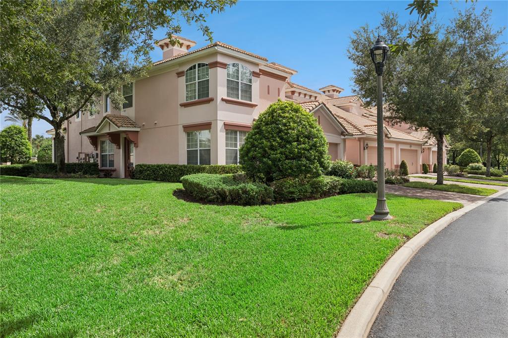 A two-story pink stucco townhouse with a tiled roof and a manicured front lawn — 1406 MILLEDGE LANE, DAVENPORT, FL