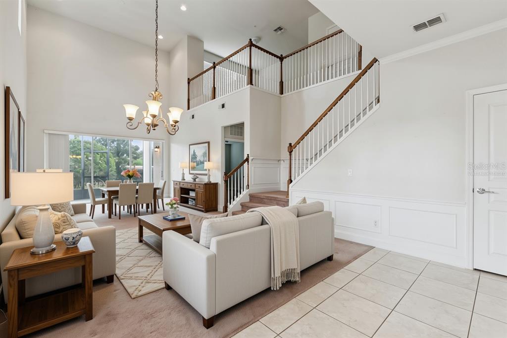 A living room with high ceilings, a staircase, and a dining area in the background — 1406 MILLEDGE LANE, DAVENPORT, FL
