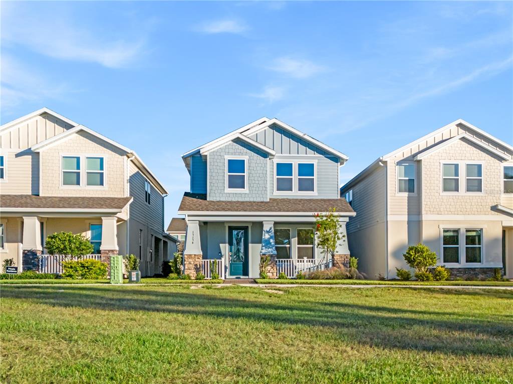 Three two-story suburban houses with light-colored siding stand side-by-side behind a grassy lawn — 15154 ALDER CHASE ALLEY, WINTER GARDEN, FL