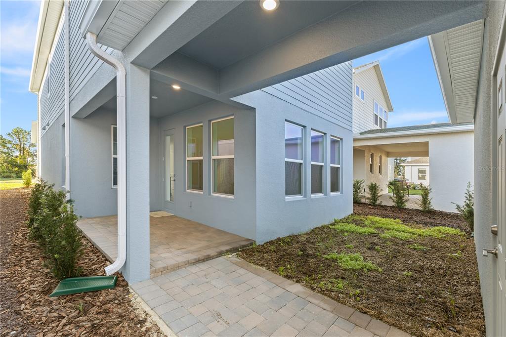 A light blue house exterior features a covered patio, paver walkway, and small landscaped yard — 15154 ALDER CHASE ALLEY, WINTER GARDEN, FL