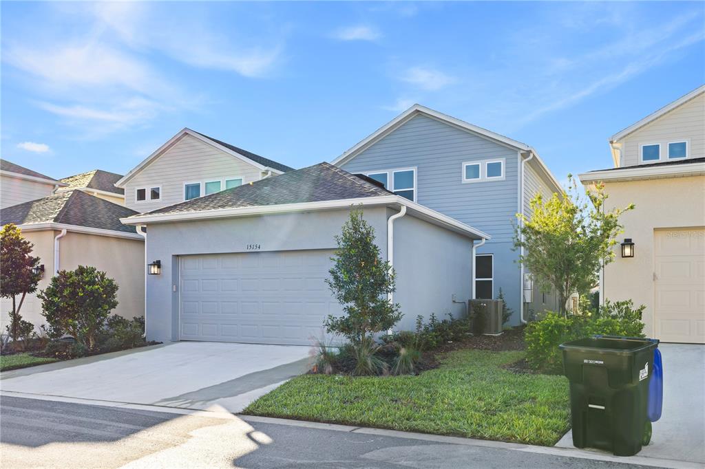 A two-story house with light blue siding, a two-car garage, and a green lawn — 15154 ALDER CHASE ALLEY, WINTER GARDEN, FL