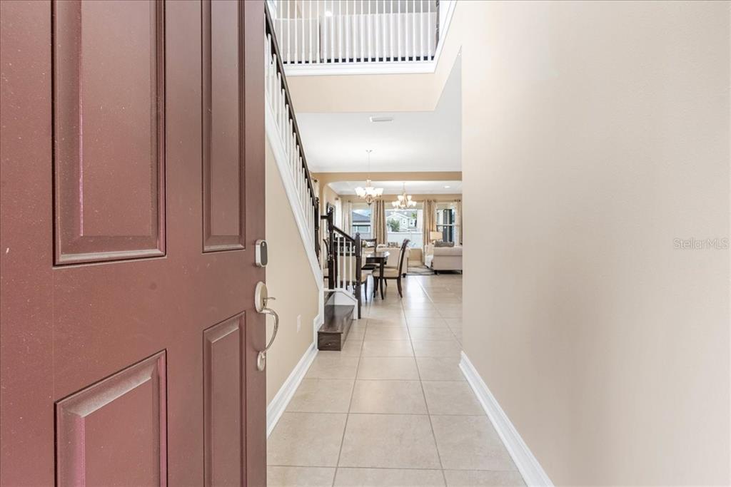 A view from an open front door into a tiled foyer with a staircase — 3963 EMPOLI COURT, WESLEY CHAPEL, FL