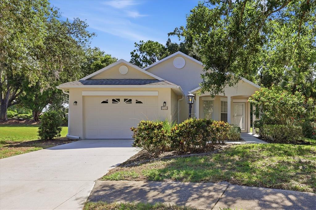 A single-story house with a beige exterior, a one-car garage, and a landscaped front yard — 12349 WOOD SAGE TERRACE, BRADENTON, FL