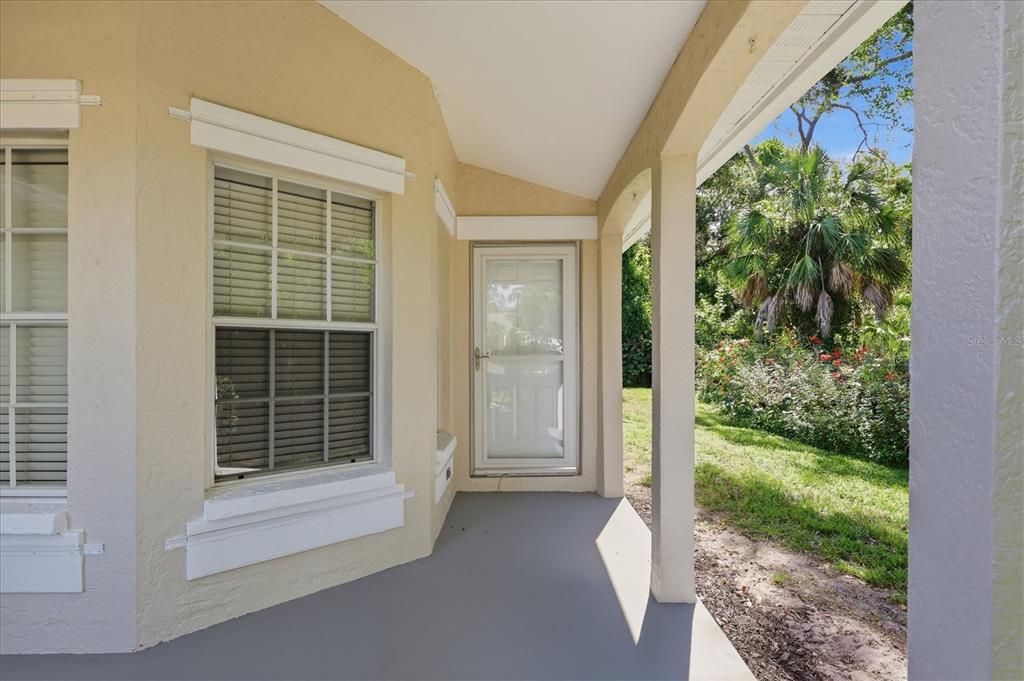 A covered porch with a gray floor, beige walls, and a white storm door — 12349 WOOD SAGE TERRACE, BRADENTON, FL