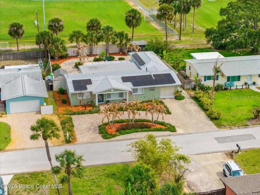 An aerial view shows a light green house with a metal roof and solar panels — 121 ALGONQUIN TERRACE, INDIAN HARBOUR BEACH, FL