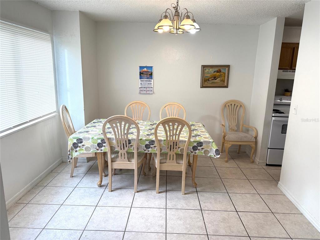 A dining room features a table with six chairs, tile flooring, and a chandelier — 5123 PICADILLY CIRCUS COURT UNIT 2, ORLANDO, FL