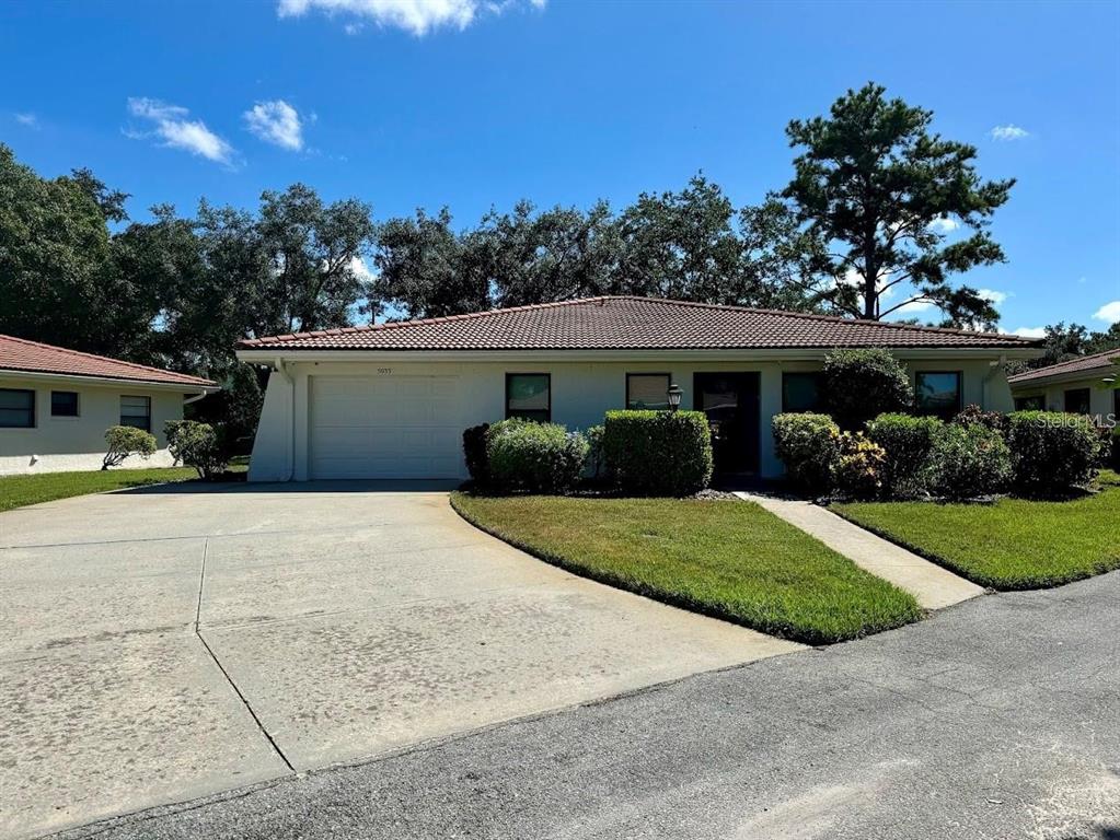 A single-story house with a tiled roof, a garage, and a concrete driveway — 5033 VIVIENDA WAY UNIT 19, SARASOTA, FL