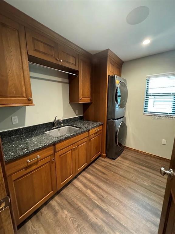 A laundry room features wood cabinets, a granite countertop, a sink, and a stacked washer-dryer — 5033 VIVIENDA WAY UNIT 19, SARASOTA, FL