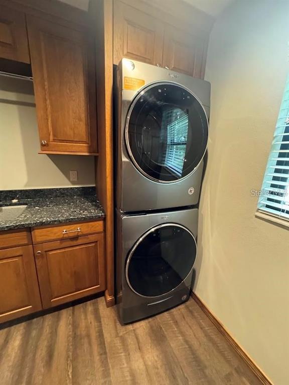 A laundry room features wood cabinets, dark granite countertops, and a stacked silver washer-dryer unit — 5033 VIVIENDA WAY UNIT 19, SARASOTA, FL