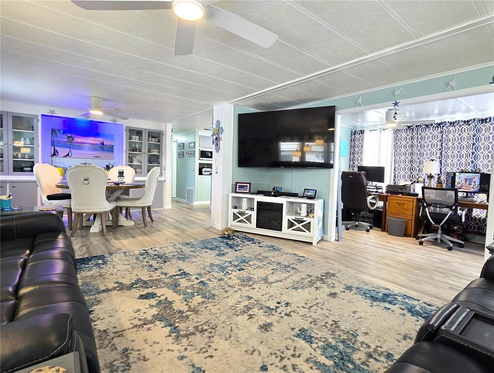 A living room features a large area rug, a wall-mounted television, and an adjacent dining area — 5619 BAYSHORE ROAD UNIT 435, PALMETTO, FL