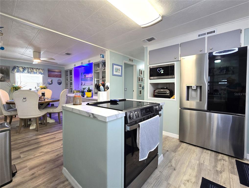 A kitchen with a central stove island, stainless steel appliances, and an adjacent dining area — 5619 BAYSHORE ROAD UNIT 435, PALMETTO, FL