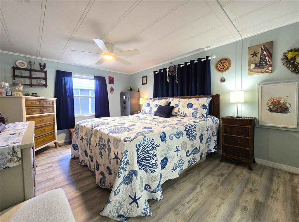 A bedroom features a coastal-themed bedspread, dark blue curtains, and light wood-look flooring — 5619 BAYSHORE ROAD UNIT 435, PALMETTO, FL