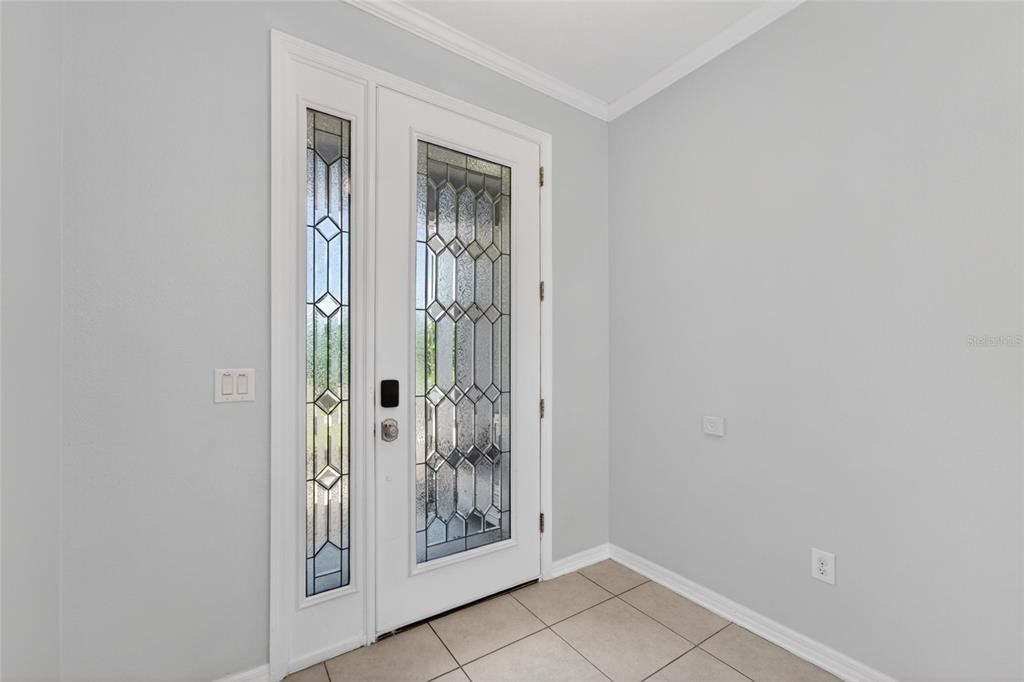 An entryway features a white front door with decorative glass panels and tiled flooring — 8108 MUDDY PINES PLACE, TAMPA, FL