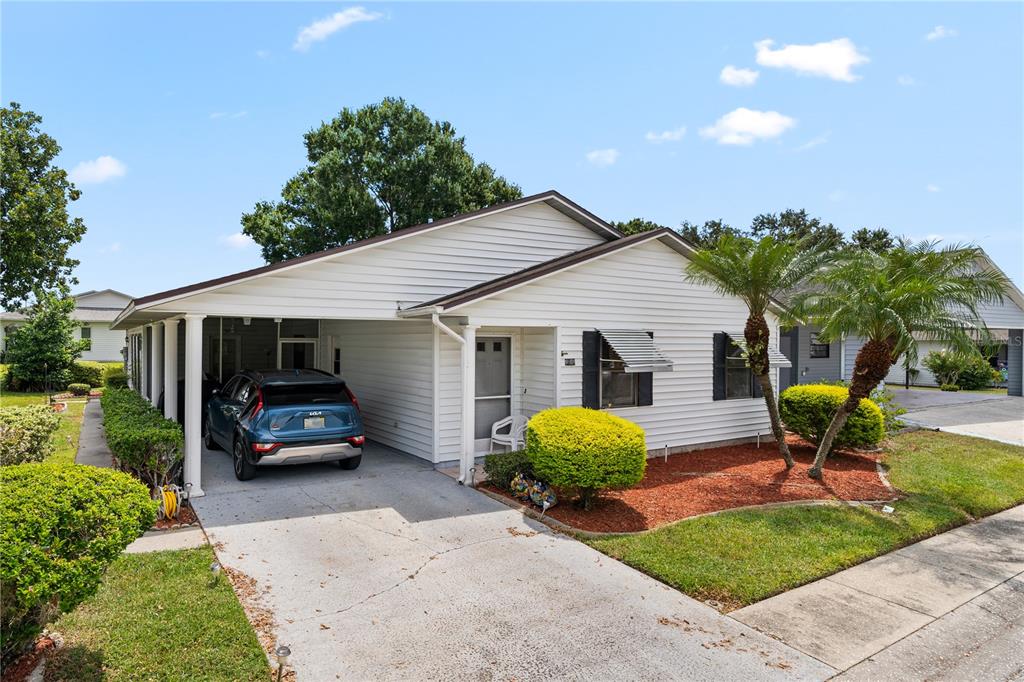 A white single-story house features a carport, a concrete driveway, and landscaped front yard — 1967 LONG BOAT DRIVE, LAKELAND, FL