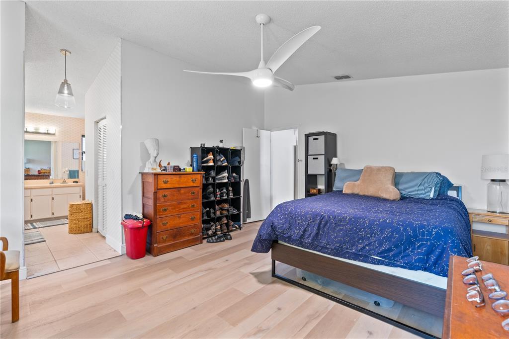 A bedroom features light wood flooring, a ceiling fan, a wooden dresser, and a bed — 1967 LONG BOAT DRIVE, LAKELAND, FL