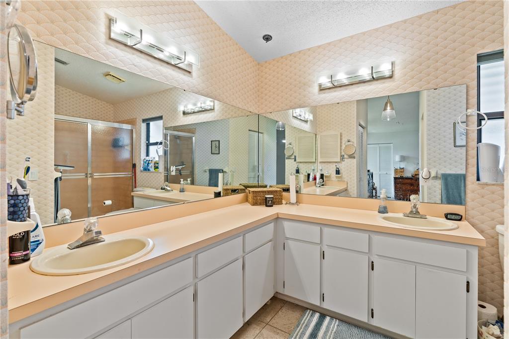 A bathroom features a double vanity with white cabinets, peach countertops, and large wall mirrors — 1967 LONG BOAT DRIVE, LAKELAND, FL