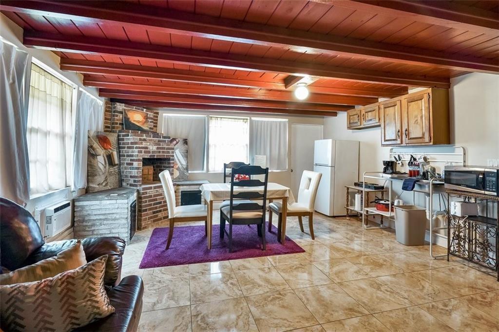 A dining area with a brick fireplace, tiled floors, and exposed wood ceiling beams — 617 Lakeside Harbour, Boynton Beach FL 33435, BOYNTON BEACH, FL