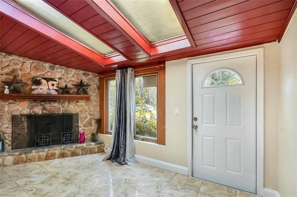 A room with a stone fireplace, tiled floor, and a red wood-paneled ceiling with skylights — 617 Lakeside Harbour, Boynton Beach FL 33435, BOYNTON BEACH, FL