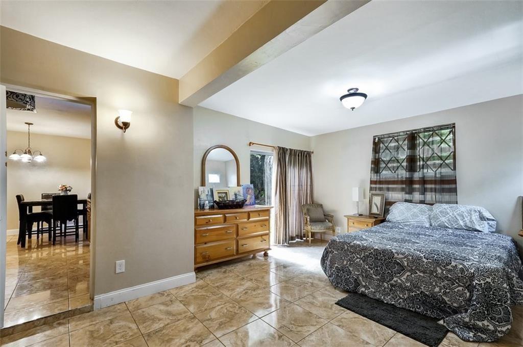 A bedroom with tile flooring, a bed, a wooden dresser, and a doorway to a dining area — 617 Lakeside Harbour, Boynton Beach FL 33435, BOYNTON BEACH, FL