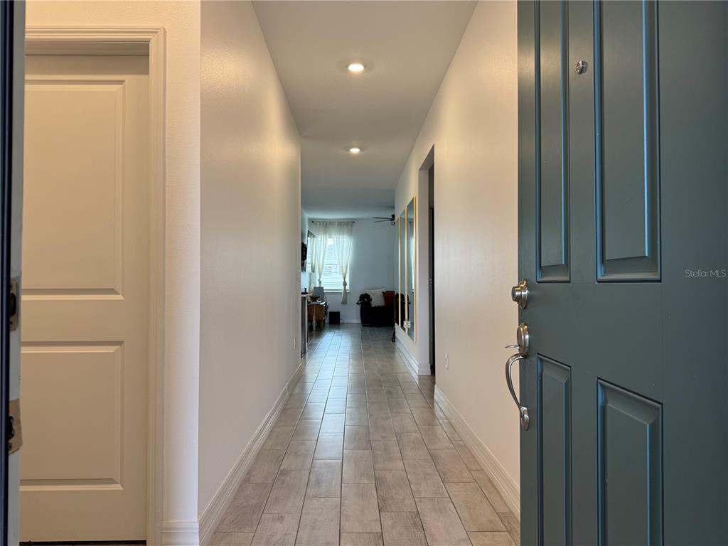 A view through an open teal door into a hallway with light-colored tile flooring — 1225 FOX HEDGE LANE, ST CLOUD, FL