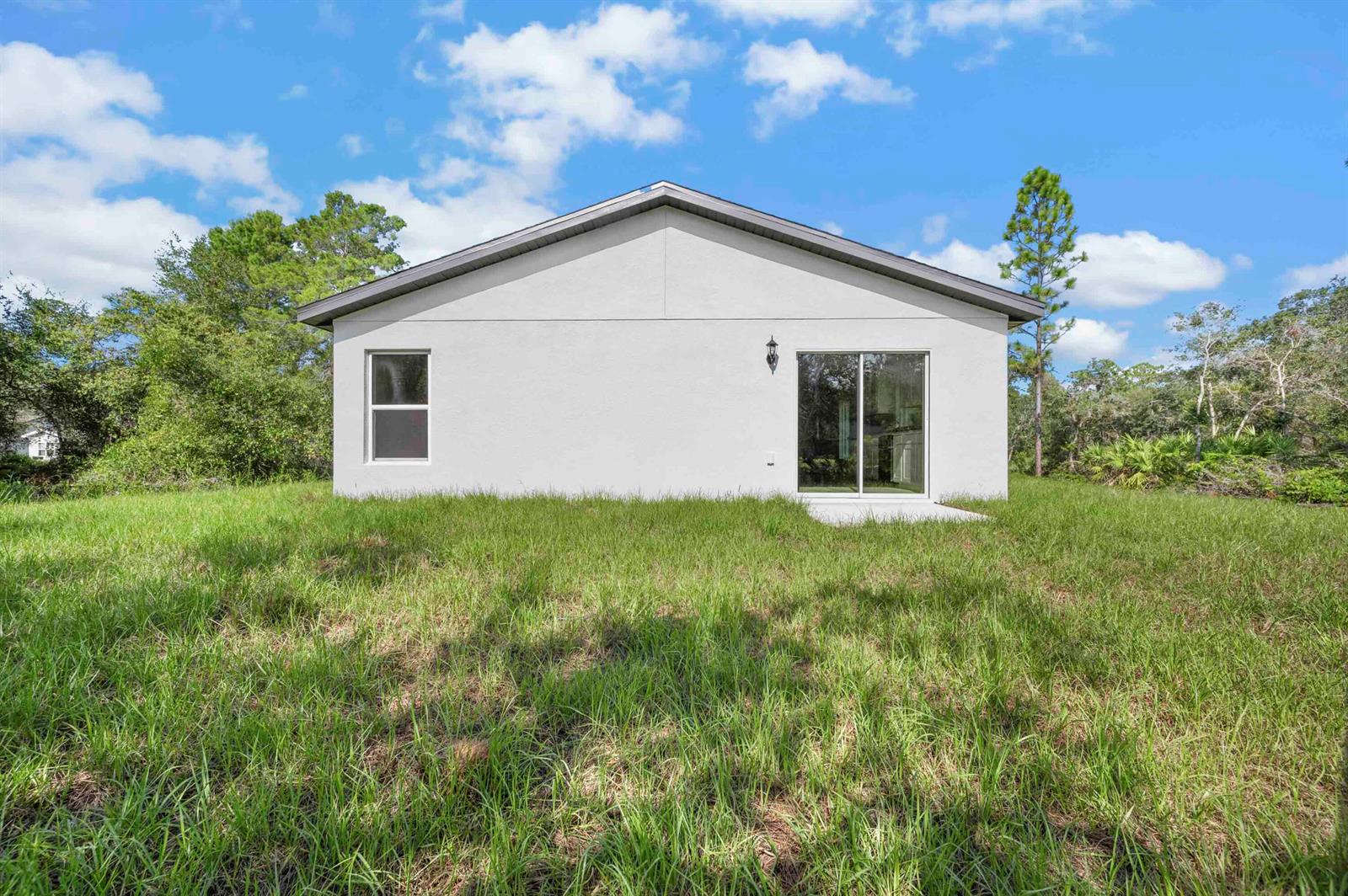 The back exterior of a white house features a sliding glass door and one window — 5717 Palm Drive, Fort Pierce FL 34982, FORT PIERCE, FL