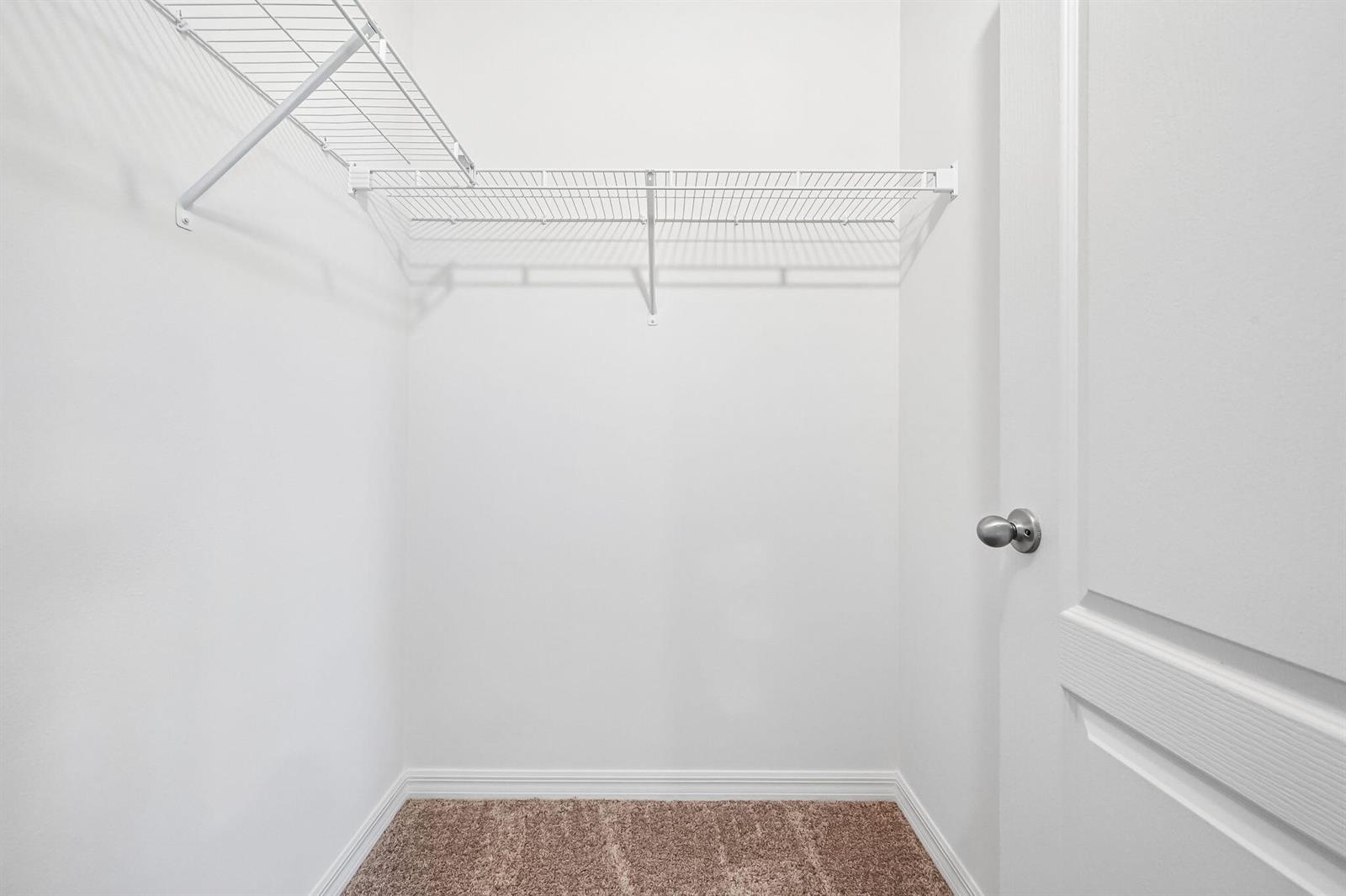 A small walk-in closet with white walls, beige carpet, and white wire shelving — 5717 Palm Drive, Fort Pierce FL 34982, FORT PIERCE, FL